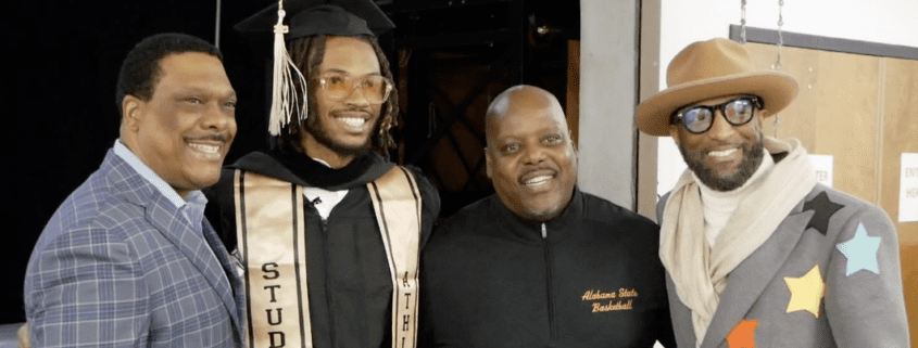 Four men smiling, one in graduation attire.